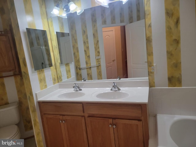 bathroom with vanity, toilet, a tub, and an inviting chandelier