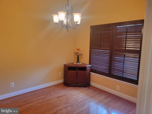 spare room with light hardwood / wood-style flooring and a chandelier