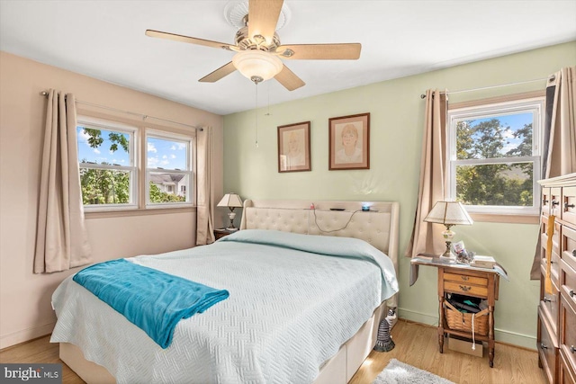 bedroom featuring ceiling fan, light hardwood / wood-style floors, and multiple windows