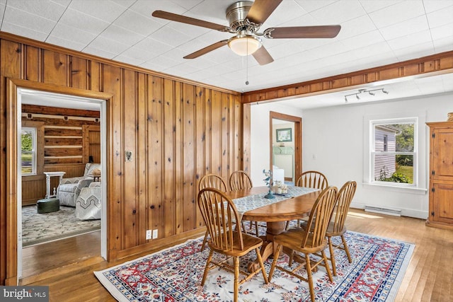 dining area featuring hardwood / wood-style flooring, ceiling fan, and wooden walls