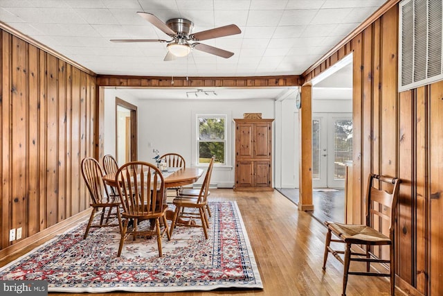 dining area with ceiling fan, wood walls, and light hardwood / wood-style flooring