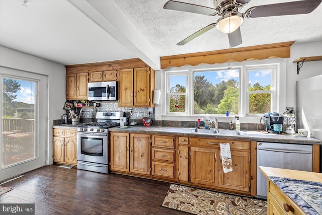 kitchen featuring beamed ceiling, sink, stainless steel appliances, and a textured ceiling