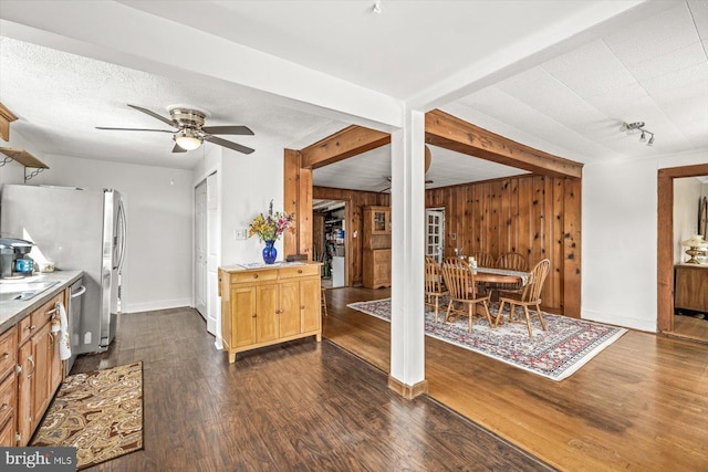 kitchen featuring ceiling fan, dark hardwood / wood-style floors, stainless steel fridge, a textured ceiling, and wooden walls