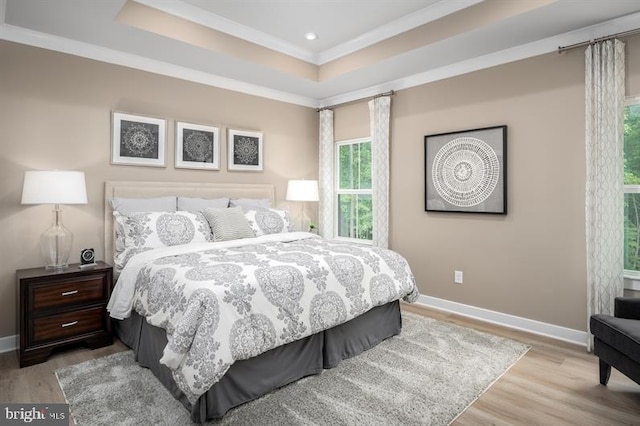 bedroom featuring light wood-type flooring, crown molding, and a raised ceiling