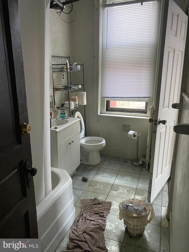 bathroom featuring tile patterned flooring, vanity, a bath, and toilet