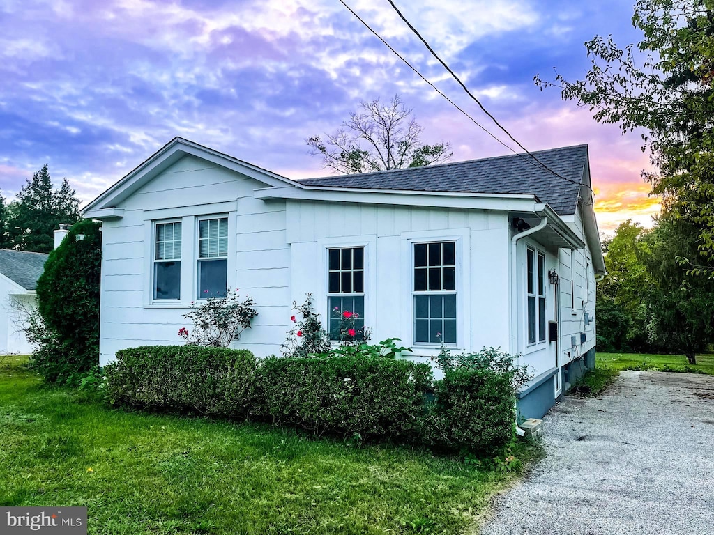 property exterior at dusk featuring a lawn