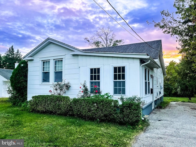 property exterior at dusk featuring a lawn