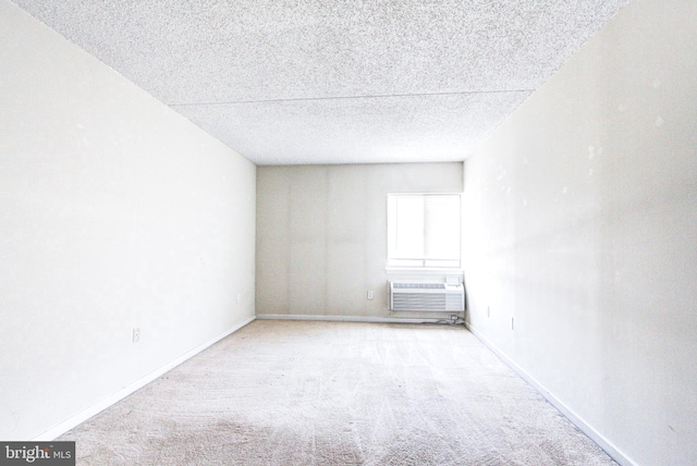 carpeted empty room with a wall unit AC and a textured ceiling