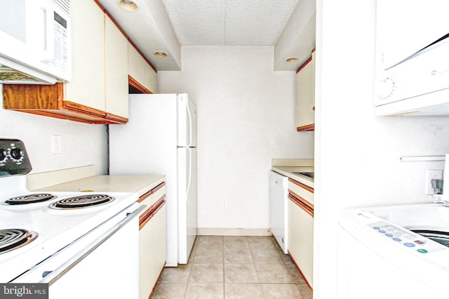 kitchen featuring white appliances, light tile patterned floors, a textured ceiling, white cabinetry, and washer / clothes dryer