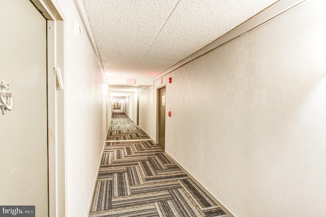 corridor featuring dark carpet and a textured ceiling