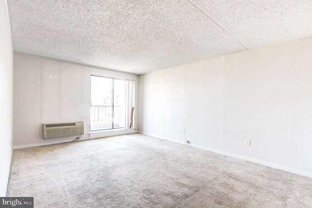 carpeted empty room with a wall mounted air conditioner and a textured ceiling