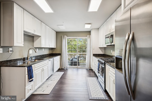 kitchen with dark stone counters, sink, dark hardwood / wood-style flooring, white cabinetry, and stainless steel appliances