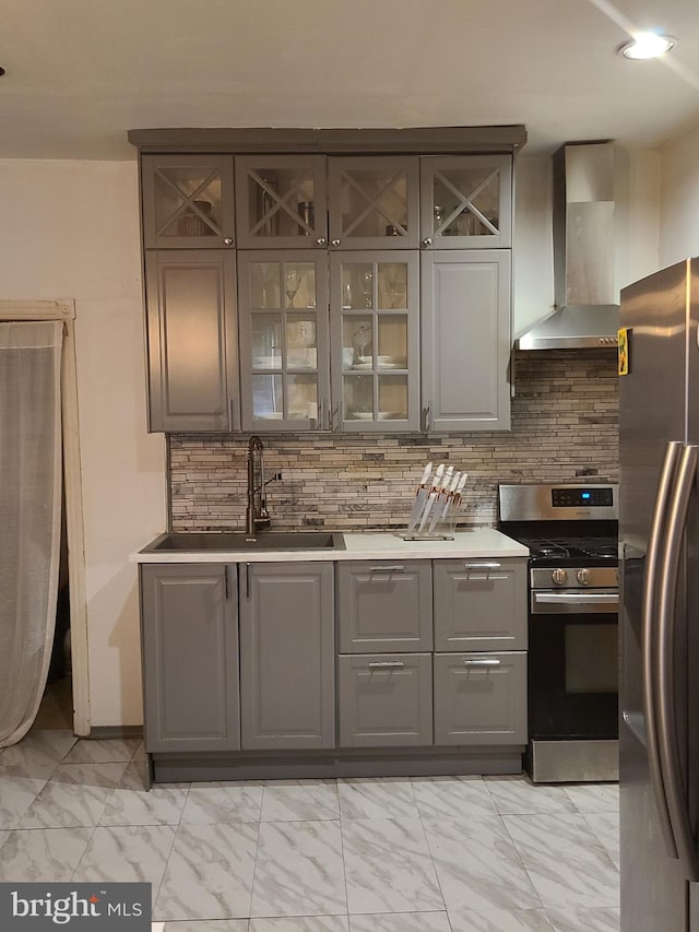 kitchen featuring decorative backsplash, appliances with stainless steel finishes, sink, and wall chimney range hood