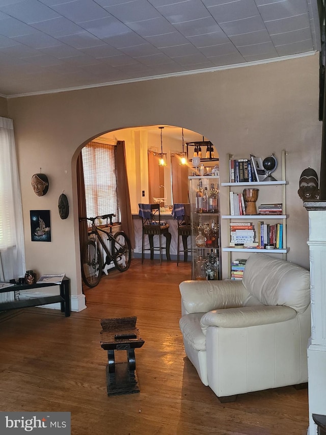 living room with wood-type flooring, ornamental molding, and a chandelier