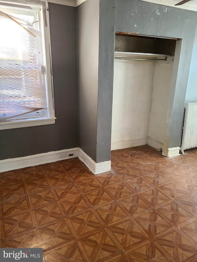 unfurnished bedroom featuring radiator heating unit, parquet flooring, and a closet