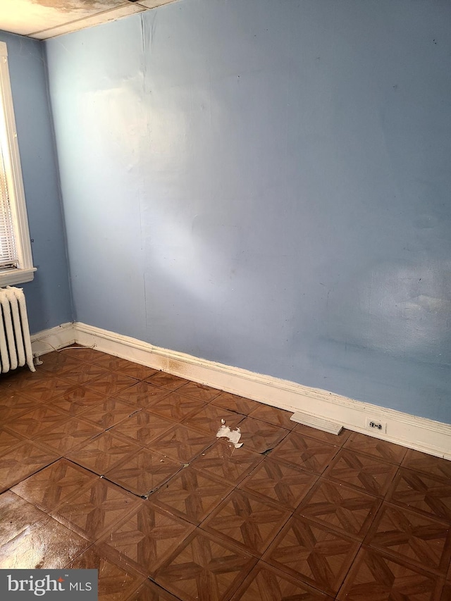 unfurnished room with radiator heating unit and parquet floors