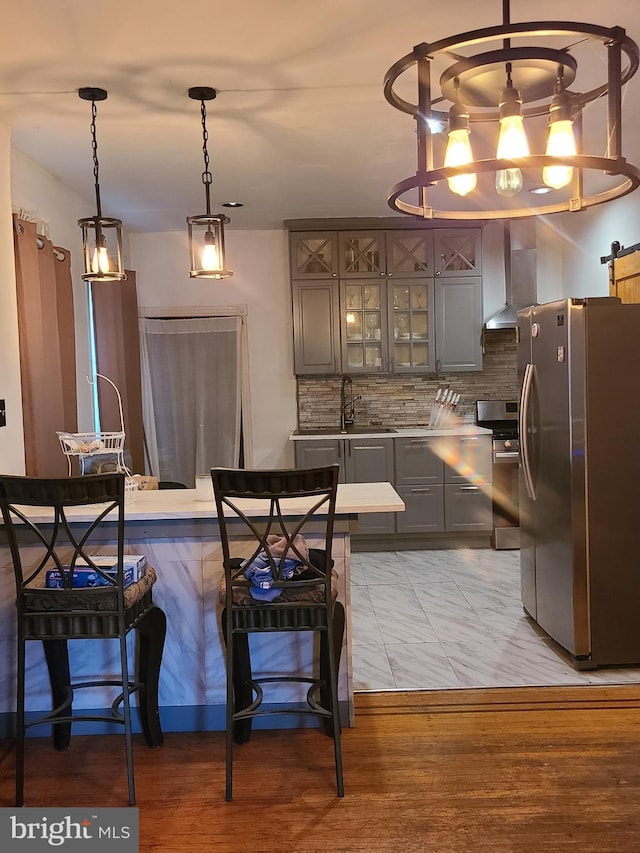 kitchen with decorative backsplash, stainless steel appliances, light hardwood / wood-style floors, and wall chimney range hood