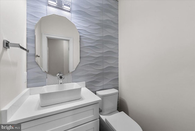 bathroom featuring toilet, tasteful backsplash, vanity, and tile walls