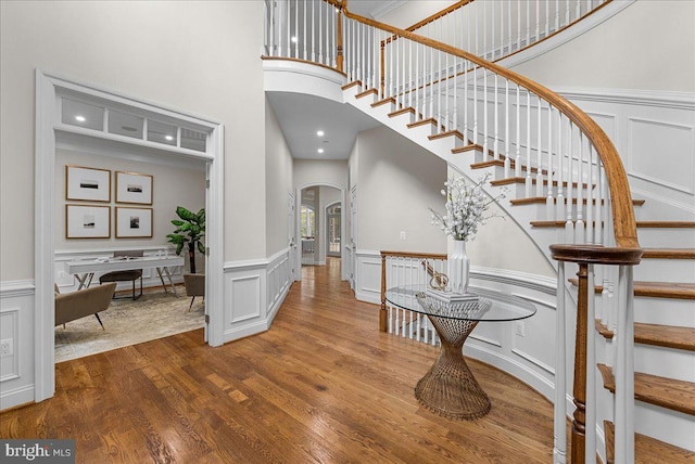 foyer entrance featuring a towering ceiling and hardwood / wood-style flooring