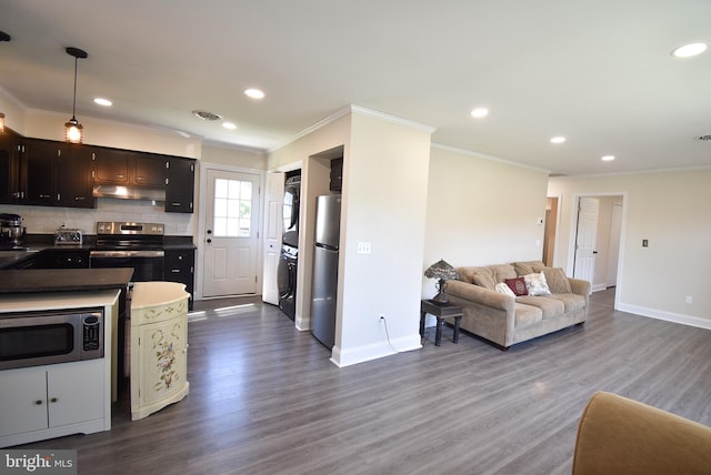 kitchen featuring decorative backsplash, stainless steel appliances, crown molding, hardwood / wood-style flooring, and stacked washer / drying machine