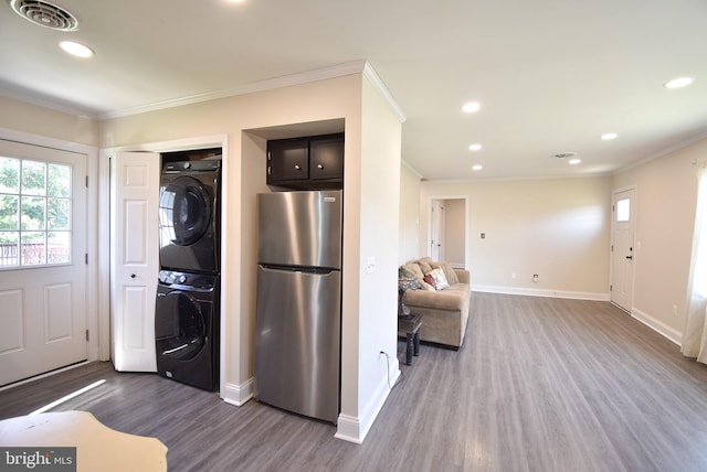 kitchen featuring stainless steel fridge, dark wood-type flooring, stacked washer and clothes dryer, and ornamental molding