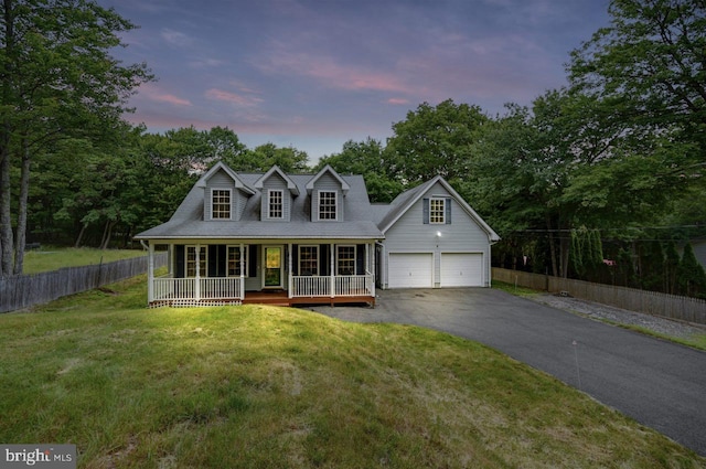 new england style home with a porch, a yard, and a garage