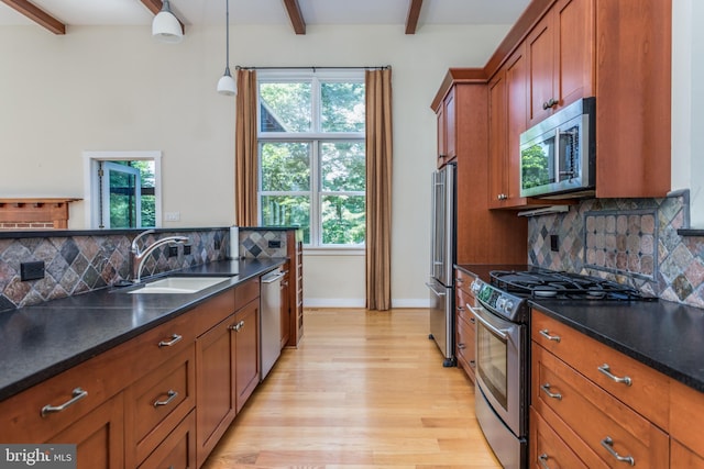 kitchen featuring beam ceiling, sink, stainless steel appliances, and plenty of natural light