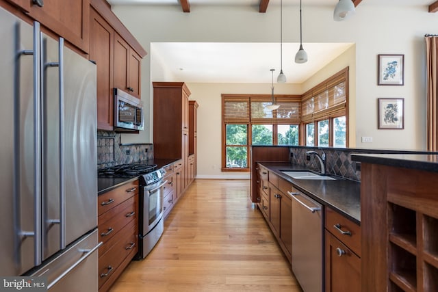 kitchen with backsplash, stainless steel appliances, hanging light fixtures, and sink