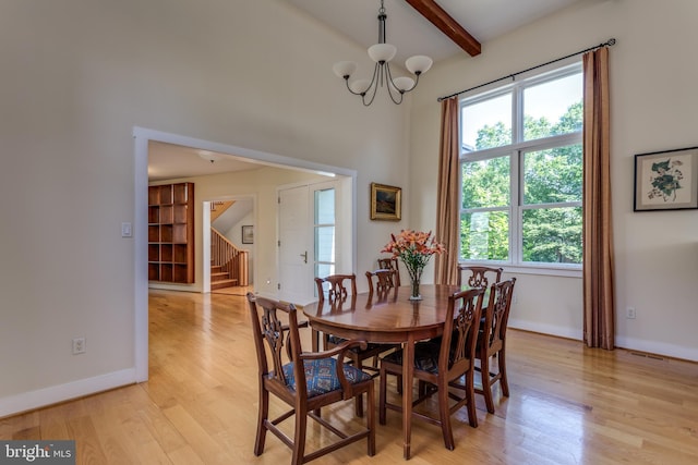 dining space featuring beam ceiling, a chandelier, and light hardwood / wood-style floors