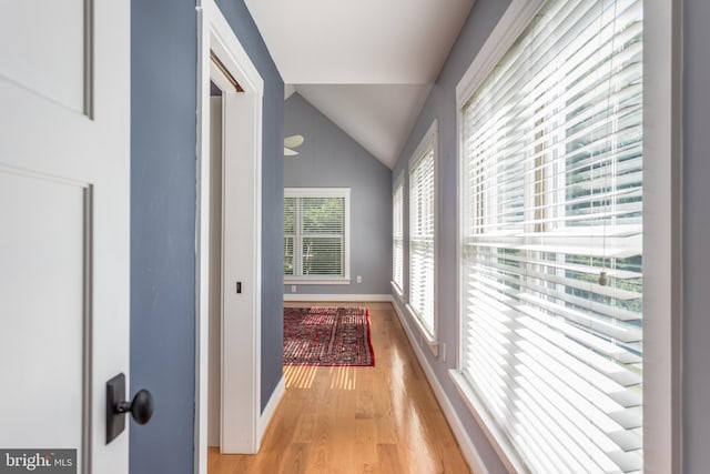 corridor with light hardwood / wood-style floors and lofted ceiling