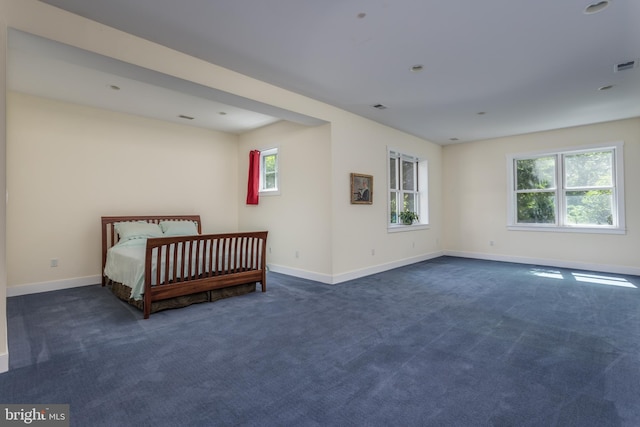 unfurnished bedroom featuring multiple windows and dark carpet