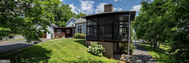 rear view of property with a sunroom and a lawn