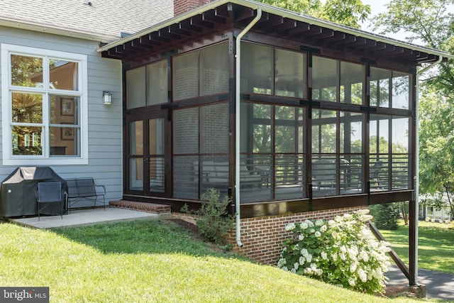 view of side of home with a lawn, a patio area, and a sunroom