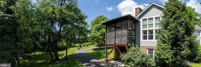 view of home's exterior with a sunroom and a yard