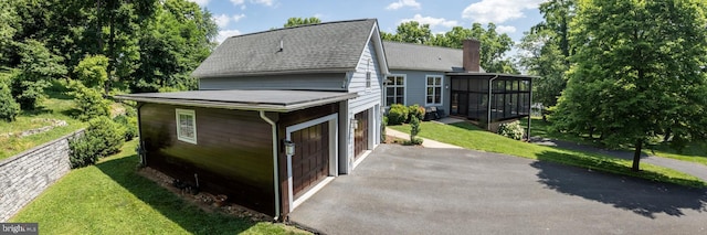 view of property exterior with a yard, a garage, and a sunroom