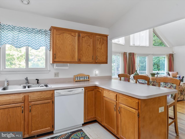 kitchen with dishwasher, a breakfast bar, lofted ceiling, sink, and kitchen peninsula