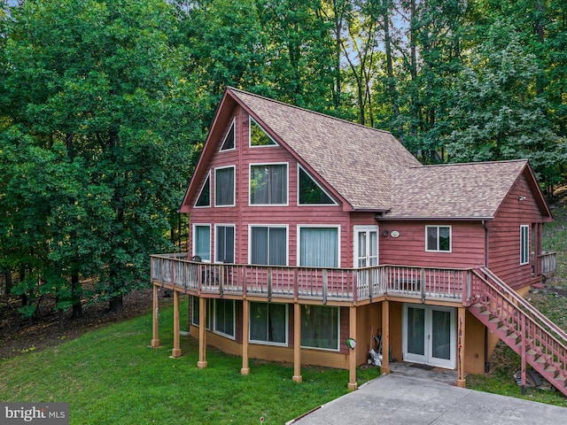 view of front of house with a wooden deck, french doors, and a front lawn