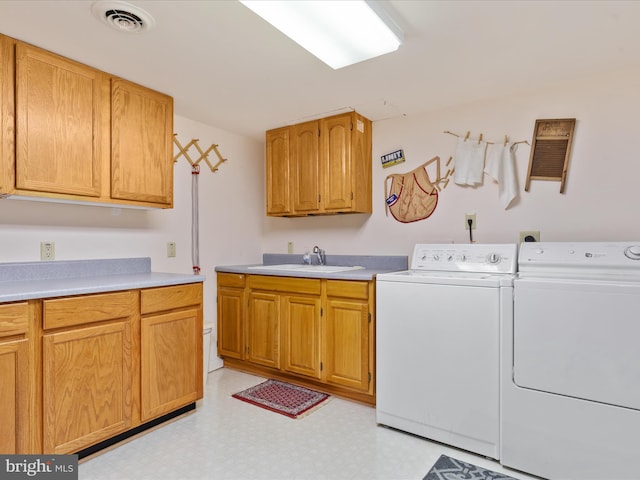 laundry room with cabinets, washing machine and clothes dryer, and sink