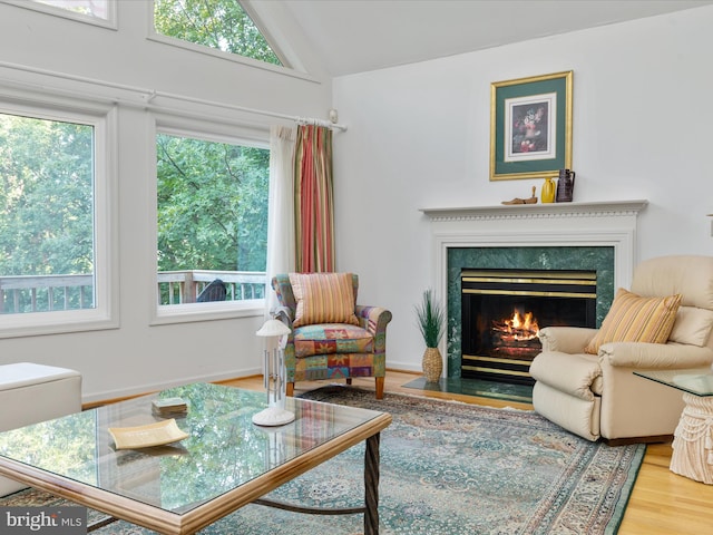 sitting room with a high end fireplace, hardwood / wood-style floors, and lofted ceiling