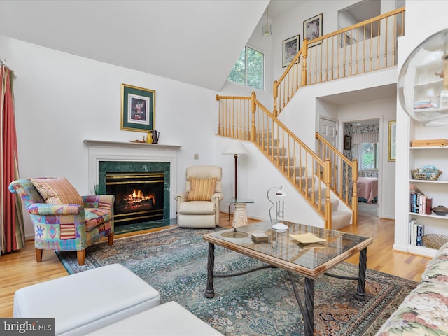 living room with hardwood / wood-style floors, a healthy amount of sunlight, a fireplace, and high vaulted ceiling