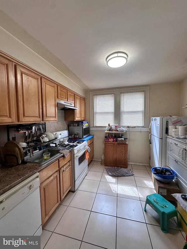 kitchen with white appliances, backsplash, sink, light tile patterned floors, and extractor fan