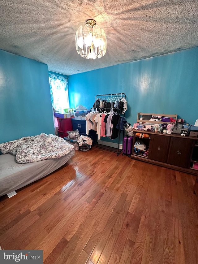 bedroom featuring hardwood / wood-style floors, a textured ceiling, and an inviting chandelier