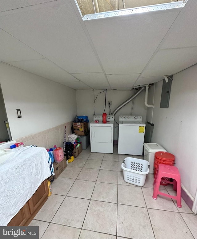 laundry area with washer and clothes dryer, light tile patterned flooring, and electric panel