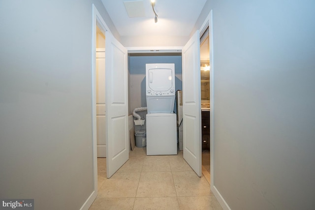 hall with light tile patterned floors and stacked washing maching and dryer