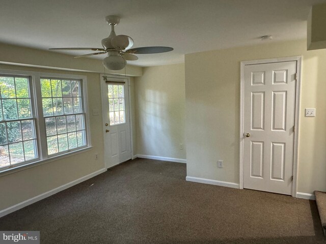 empty room featuring ceiling fan and dark colored carpet