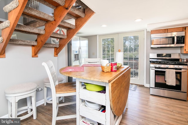 kitchen with appliances with stainless steel finishes and light hardwood / wood-style floors