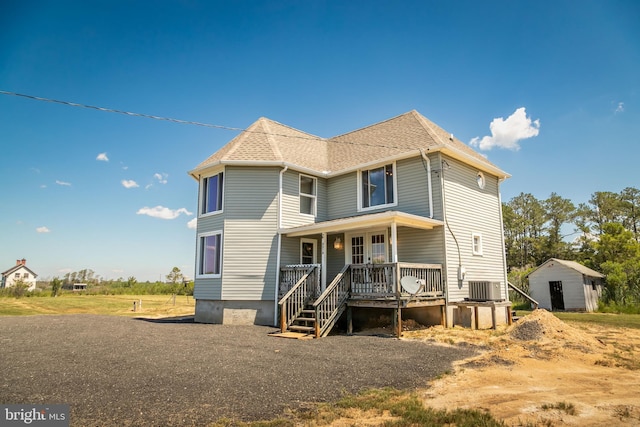 back of property with cooling unit and covered porch