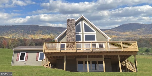 back of property featuring a deck with mountain view and a yard