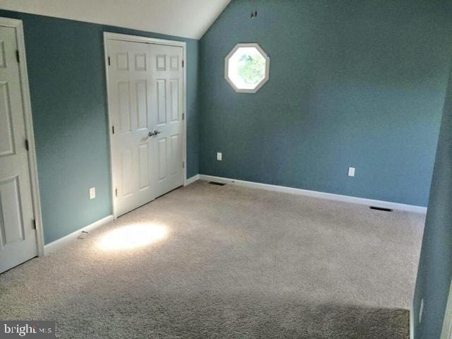 unfurnished bedroom featuring light colored carpet and vaulted ceiling