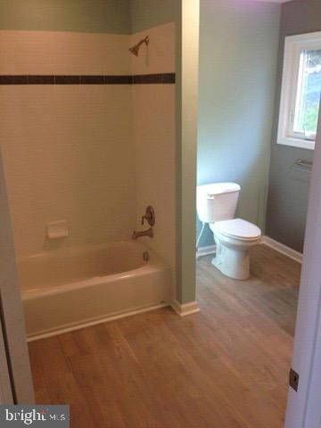 bathroom featuring toilet, tiled shower / bath combo, and hardwood / wood-style flooring